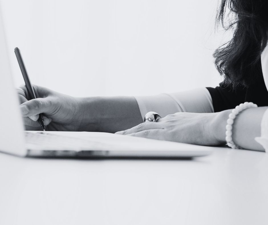 woman writing with laptop nearby